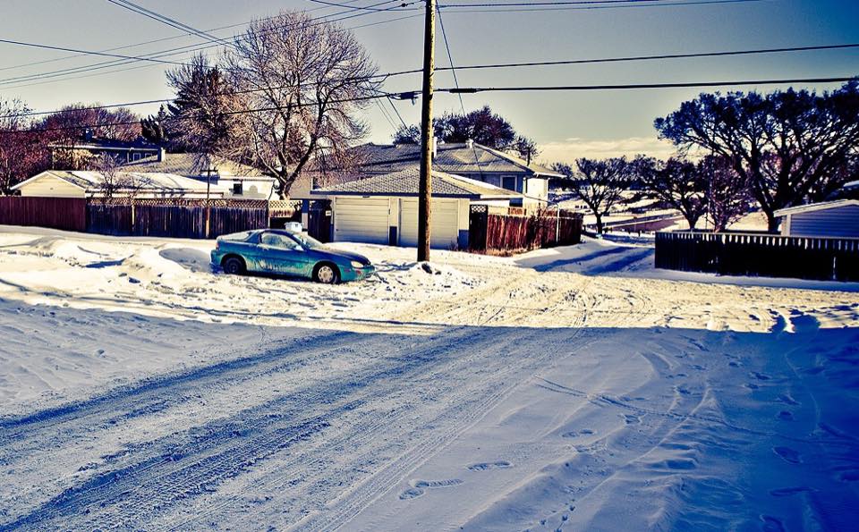 A snow-covered residential street of bungalows in Calgary on a bright February morning